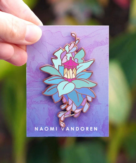 Enamel pin featuring a lantern and leaves design by Naomi VanDoren, perfect for adventure-themed accessories.