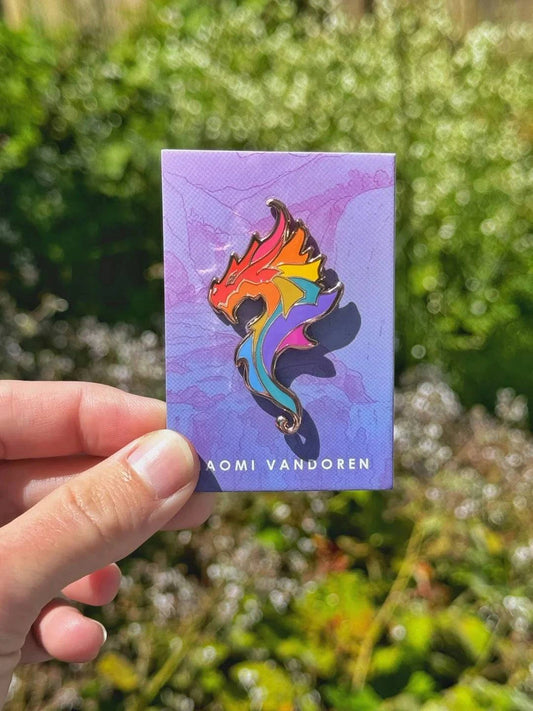 Colorful rainbow dragon enamel pin by Naomi VanDoren featuring vibrant details and intricate design on a metal backing.