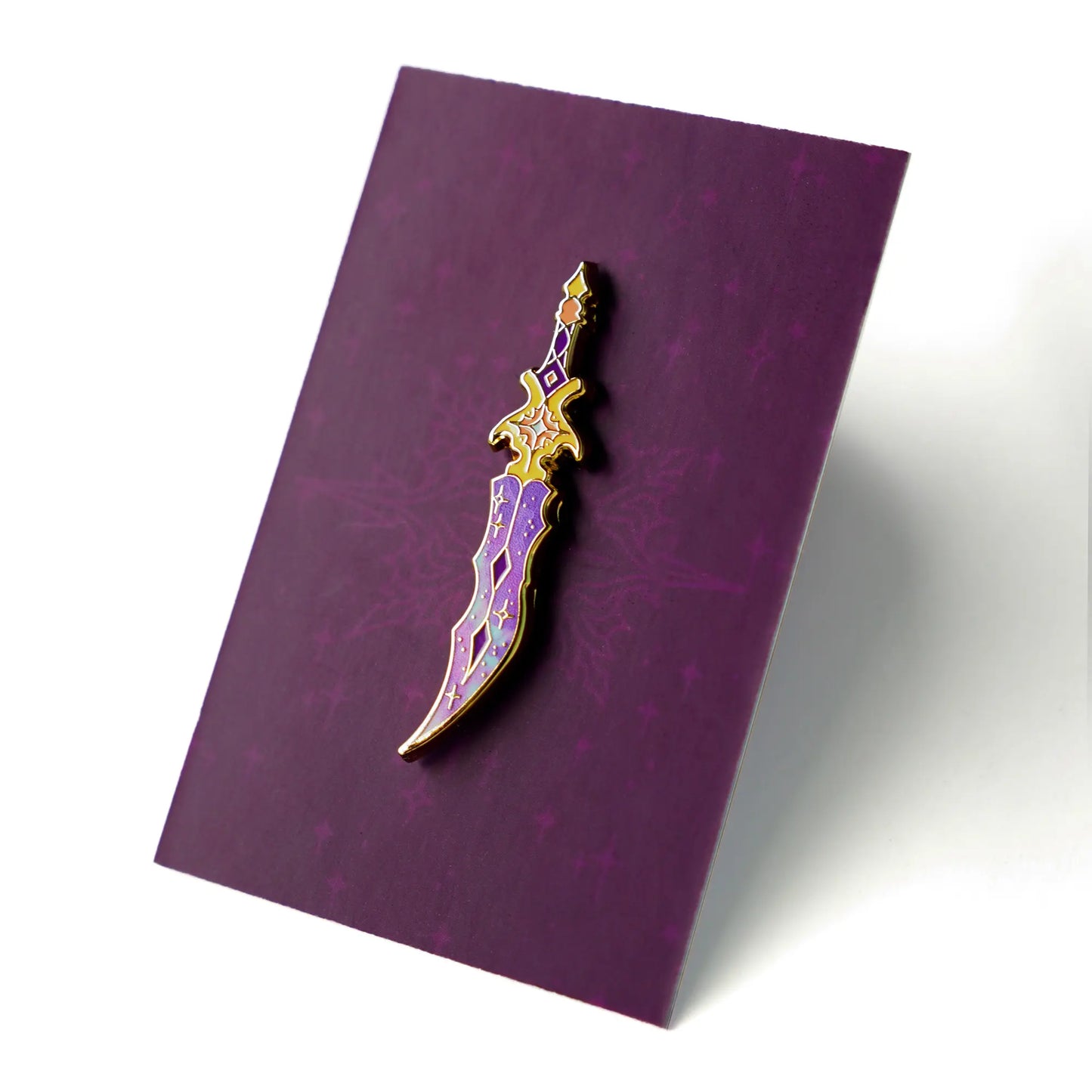 Celestial Armory Nebula Dagger enamel pin by Naomi VanDoren featuring a cosmic-themed dagger with vibrant colors and detailed design.
