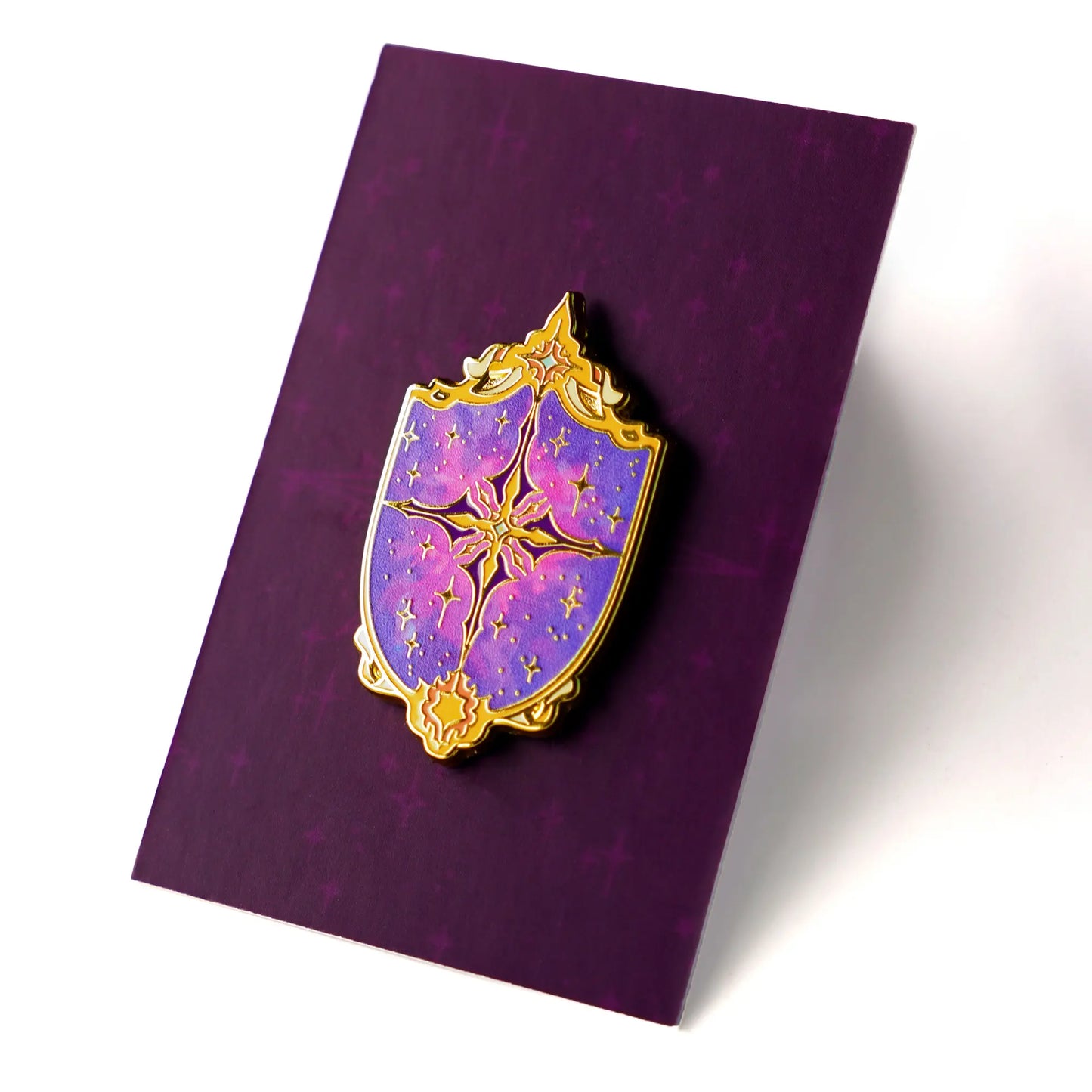 Celestial Armory Constellation Shield enamel pin by Naomi VanDoren featuring a starry shield design on a black background.